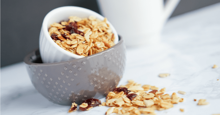 Baked Granola in a bowl next to a cup of coffee.