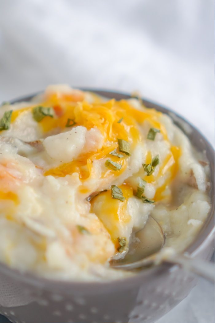 A bowl of creamy mashed potatoes with cheese and chives.