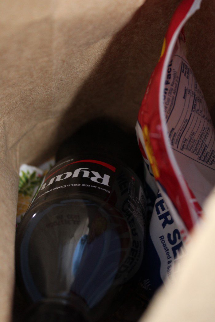 A "7 Budget Friendly Date Ideas" brown paper bag with a bottle of coca cola and a bag of chips.