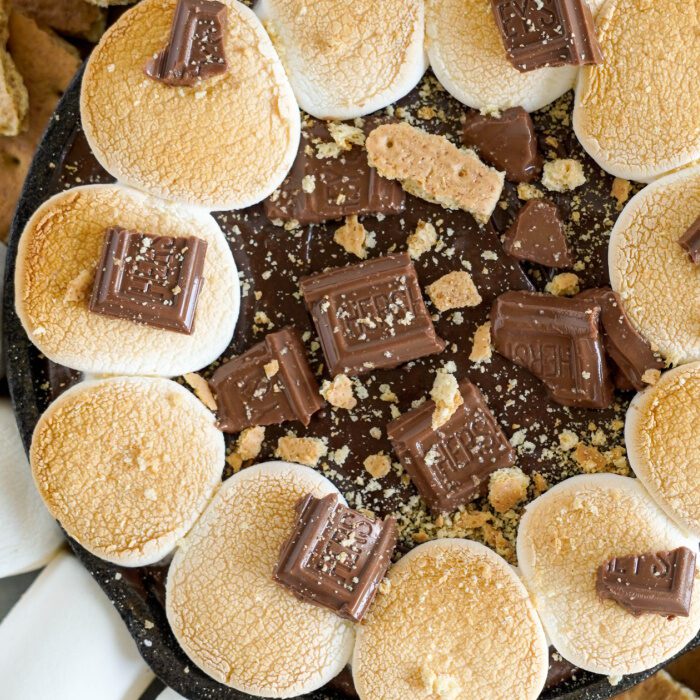 A skillet of melted chocolate, graham crackers, and marshmallows.