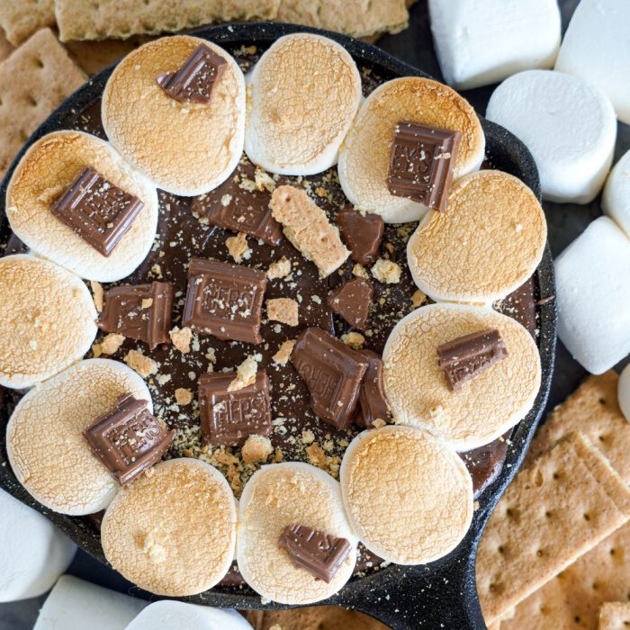 A skillet of melted chocolate with graham crackers and marshmallows.