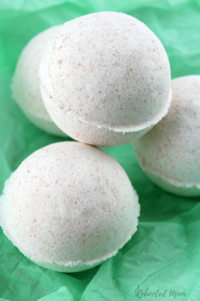 Three white homemade bath bombs stacked on top of green paper.