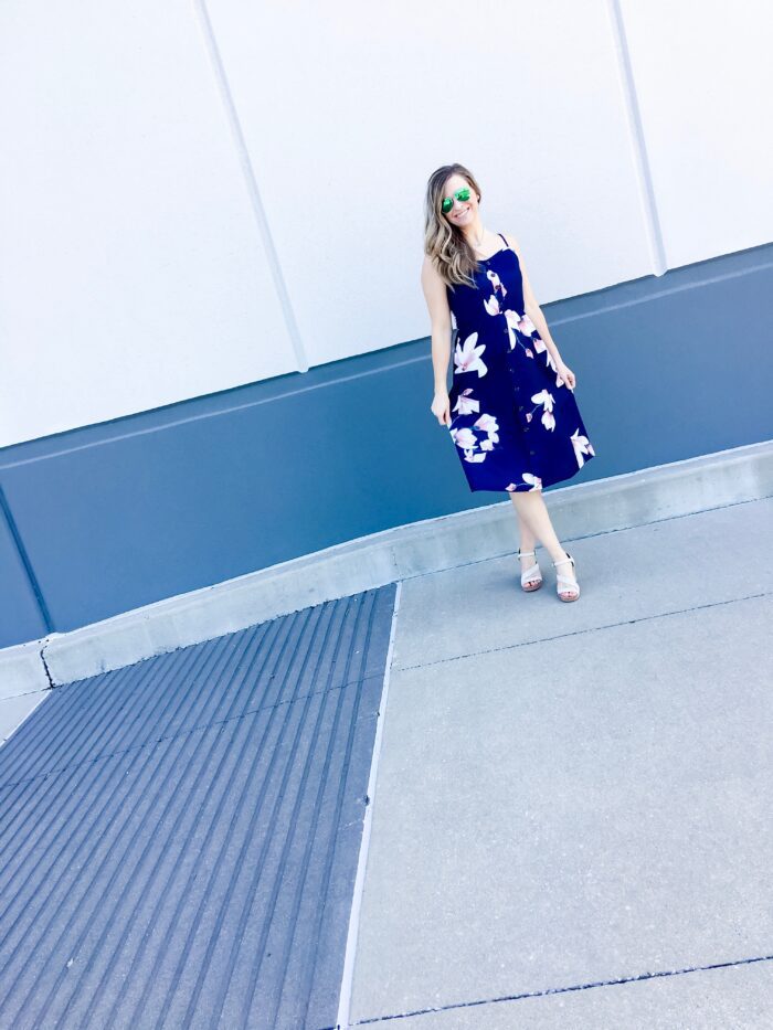 A woman wearing a blue floral dress and sunglasses.