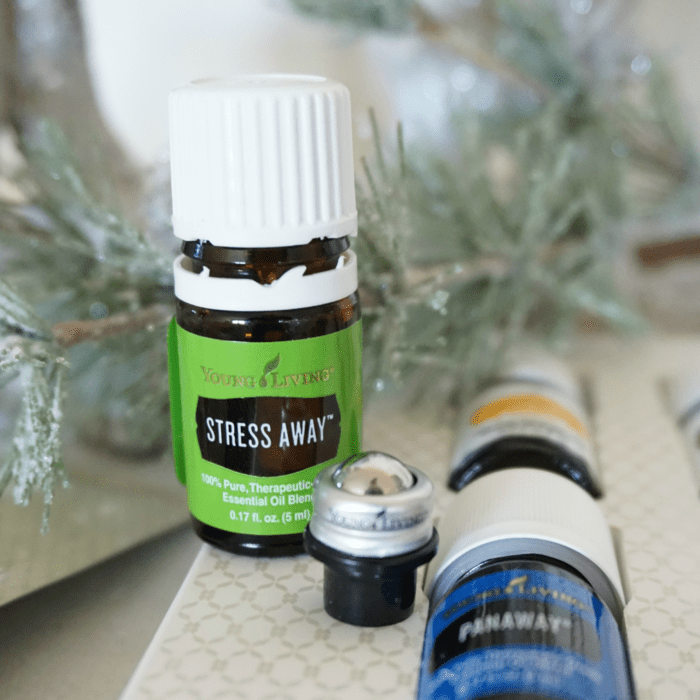 Essential oils on a table next to a Christmas tree, showcasing how to get the best price on a Young Living Premium Starter Kit.