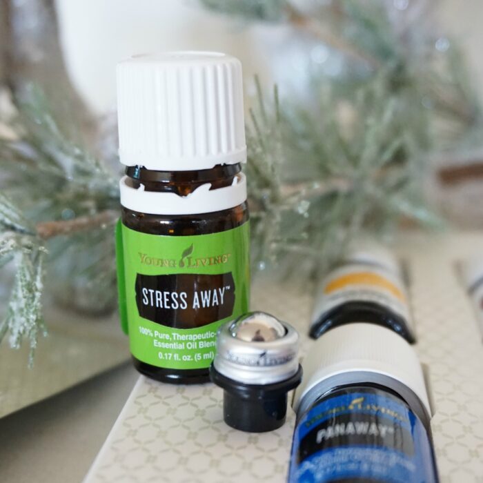Essential oils, including those from the Young Living Premium Starter Kit, on a table next to a Christmas tree.