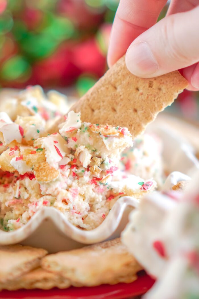 Someone Dipping a Cracker into Christmas Tree Cake Dip