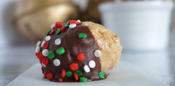 A Christmas peanut butter ball covered in chocolate and sprinkles.