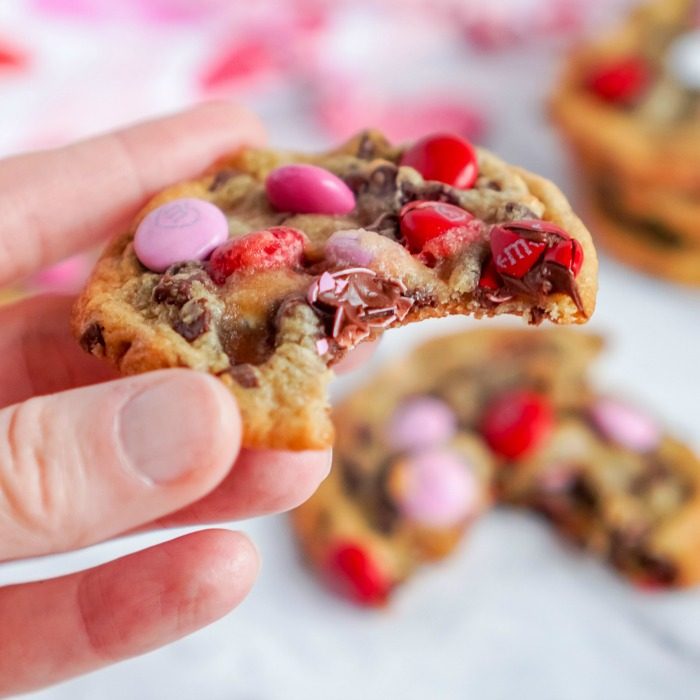 A hand holding a bitten Valentine's Day cookie.