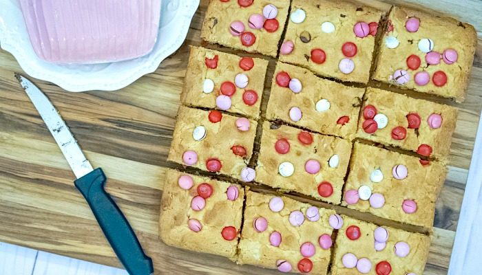 Valentine's Day Chocolate Chip Cookie Bars on a cutting board with a knife.