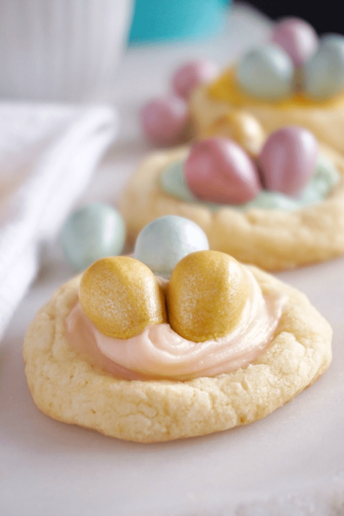 Easy Cadbury Birds Nest Easter sugar cookies with colored eggs on a white plate.