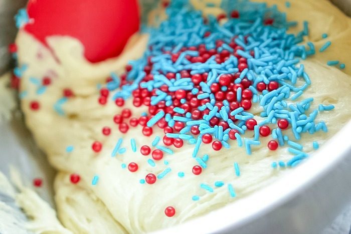 Red, white, and blue sprinkles in a mixing bowl for Homemade Sugar Cookie Bars for the 4th of July.