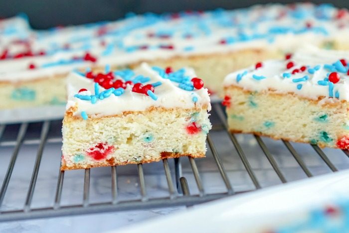 A slice of homemade red, white, and blue cake on a cooling rack.