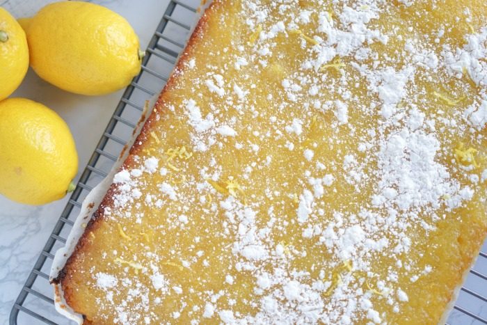 Easy Homemade Lemon Cake with powdered sugar on a cooling rack.