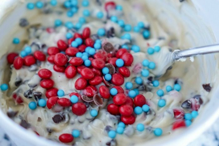 A white bowl filled with red, white and blue sprinkles for the Chocolate Chip Cookie Dough Fruit Dip on the 4th of July.