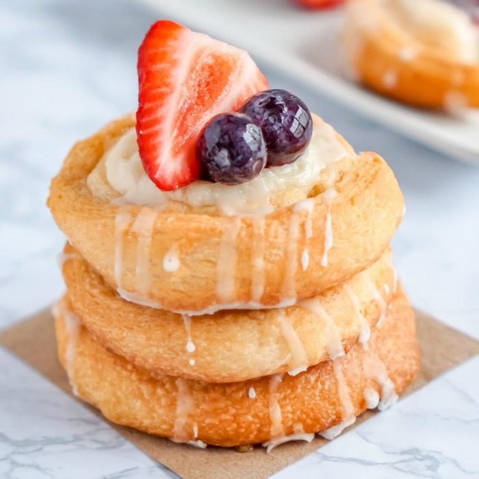 A stack of Easy Crescent Roll Cream Cheese Danish pastries with berries and icing.