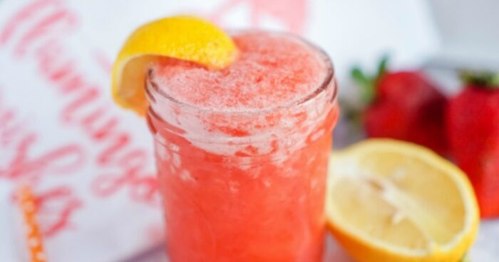 A Strawberry Lemonade Recipe in a glass with a slice of lemon.