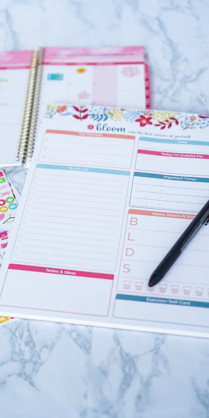 A notebook and pen, essential for easy calendar and organization hacks, on a marble table.