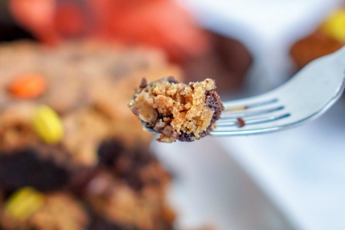 A fork is holding a piece of Easy Pumpkin Peanut Butter Brownie on a plate.