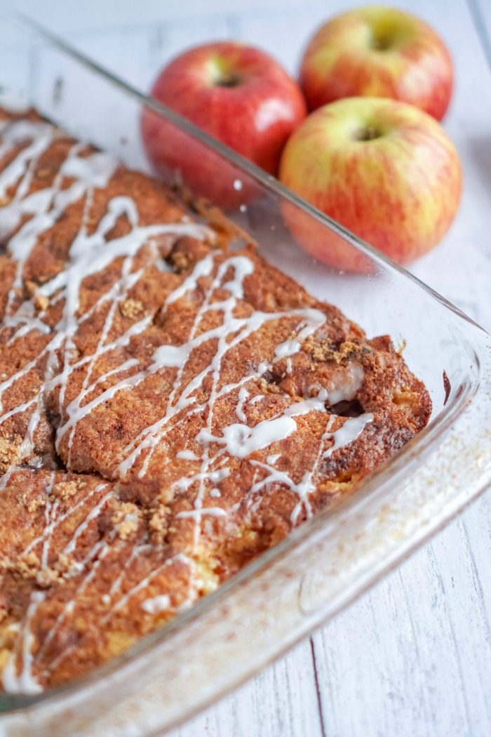 An apple coffee cake recipe with pecans in a glass dish with icing.