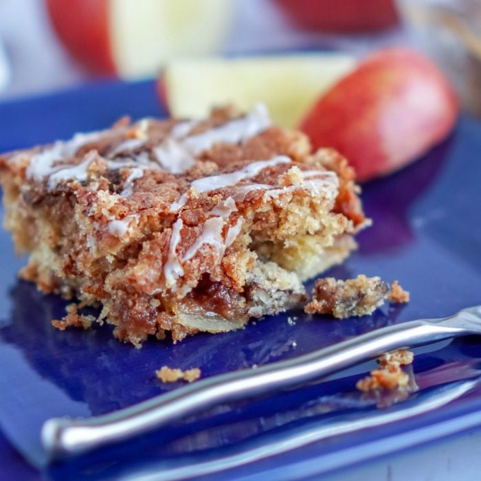A piece of apple coffee cake with pecans on a blue plate.