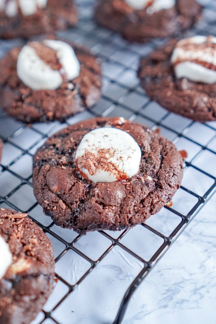 Chocolate cookies with marshmallows on a cooling rack, following an easy hot chocolate cocoa cookies recipe.