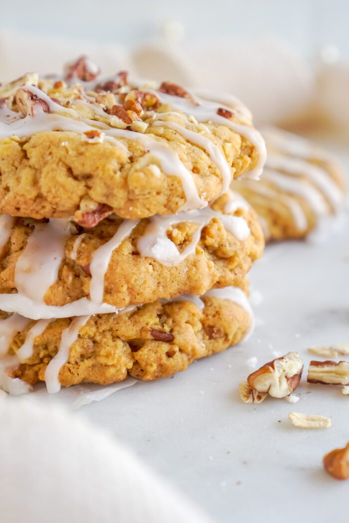 A stack of three oatmeal cookies with white icing and chopped pecans.