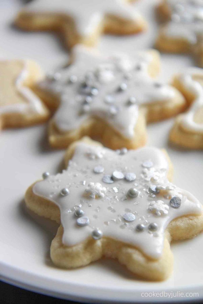 A plate of amazing cookies decorated with white icing and silver sprinkles for Christmas.