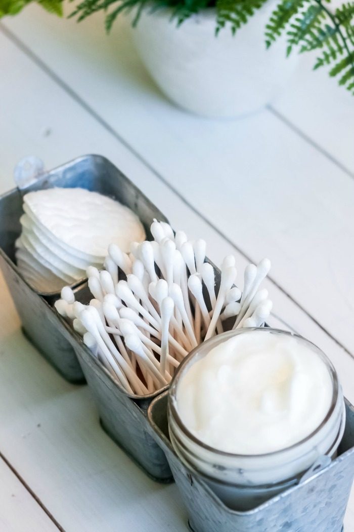 A jar of DIY homemade whipped body butter and cotton swabs in a metal container.