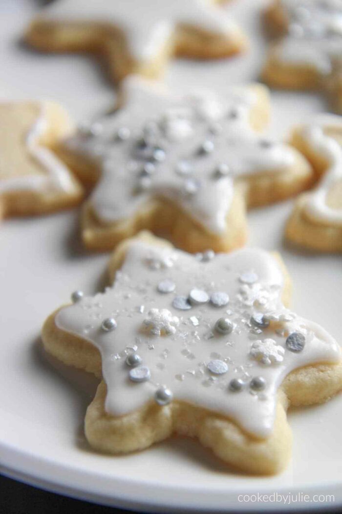 A plate of amazing Christmas cookies decorated with white icing and silver sprinkles.