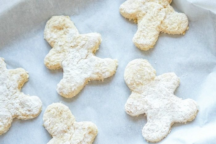 Homemade gingerbread cookies with powdered sugar on a baking sheet.