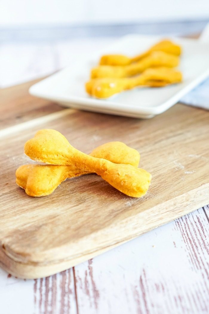 A wooden cutting board with easy homemade pumpkin dog treats on it.