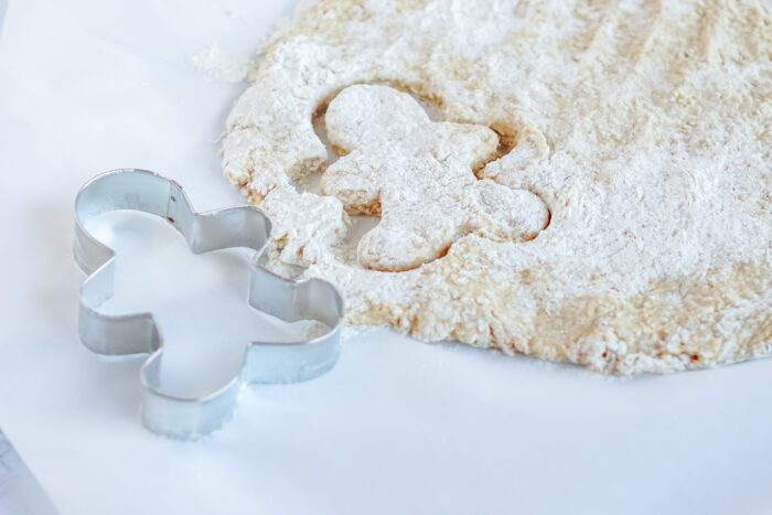 A homemade gingerbread cookie cutter with powdered sugar next to it.