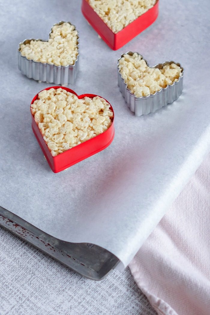 Valentine's Day heart-shaped Rice Krispie treats on a baking sheet.