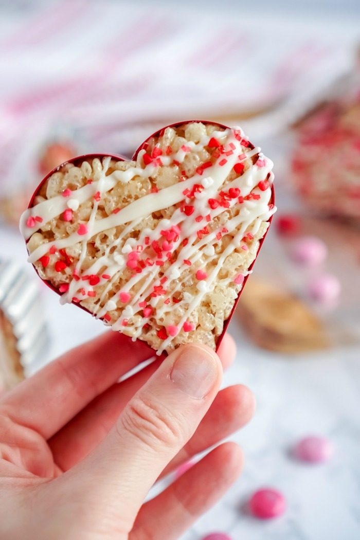 A person holding a Valentine's Day heart-shaped Rice Krispie treat.