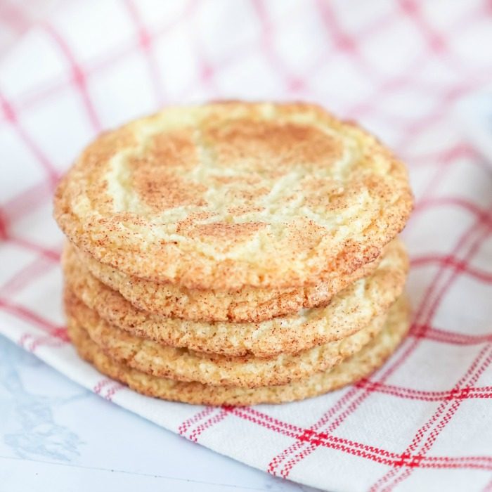 A stack of easy snickerdoodle cookies without cream of tartar on a red and white checkered tablecloth.