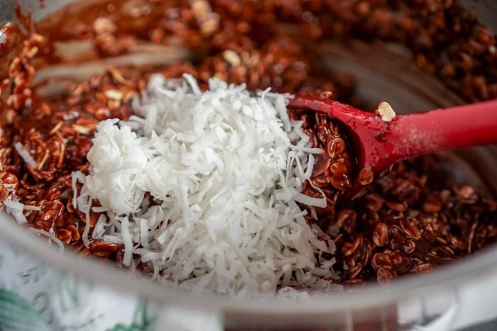 A bowl of chocolate, shredded coconut, and peanut butter with a red spatula.