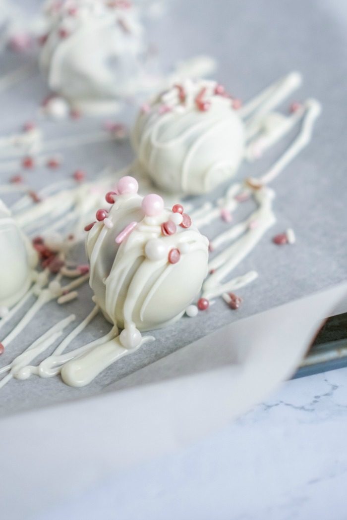 Valentine's day No Bake Oreo Cheesecake Balls with white chocolate and pink sprinkles.