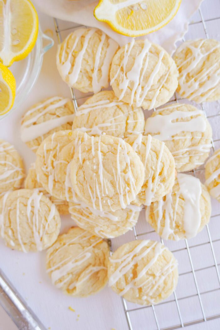 Lemon sugar cookies with glaze on a cooling rack, garnished with lemon slices.