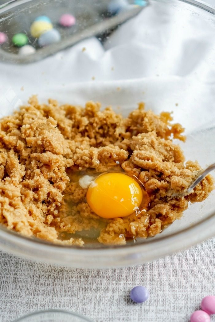 An egg in a bowl next to a bowl of granola for an easy cookie bar blondie recipe for Easter.