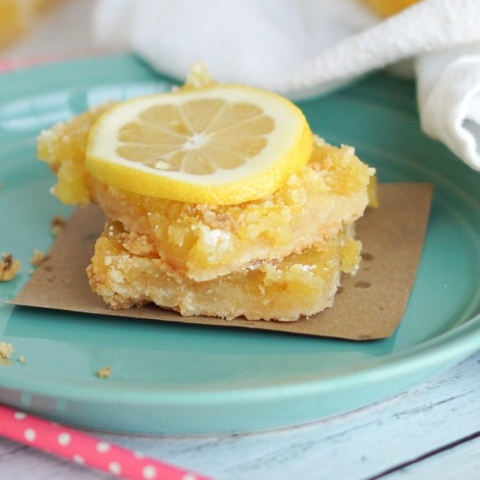 Amazing lemon bars on a plate with a slice of lemon.