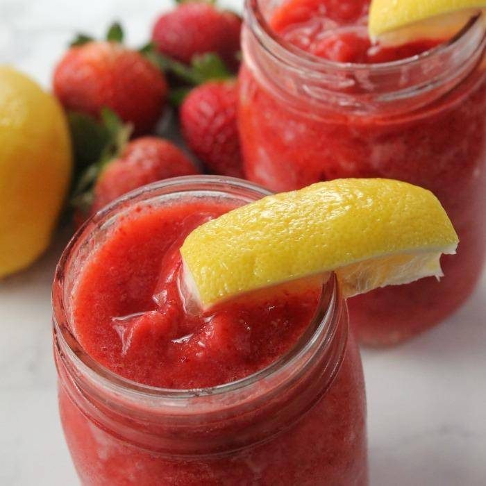 Amazing strawberry lemonade in mason jars with a slice of lemon.