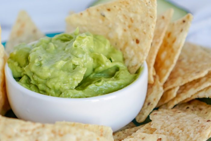 A bowl of guacamole salsa with tortilla chips.