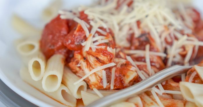 A plate of pasta with chicken and tomato sauce.