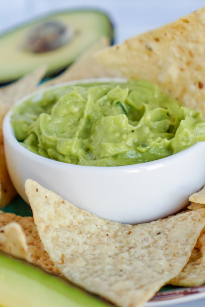 A bowl of guacamole salsa with chips and tortillas.