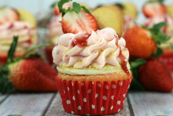 A cupcake with strawberry frosting and a strawberry on top.