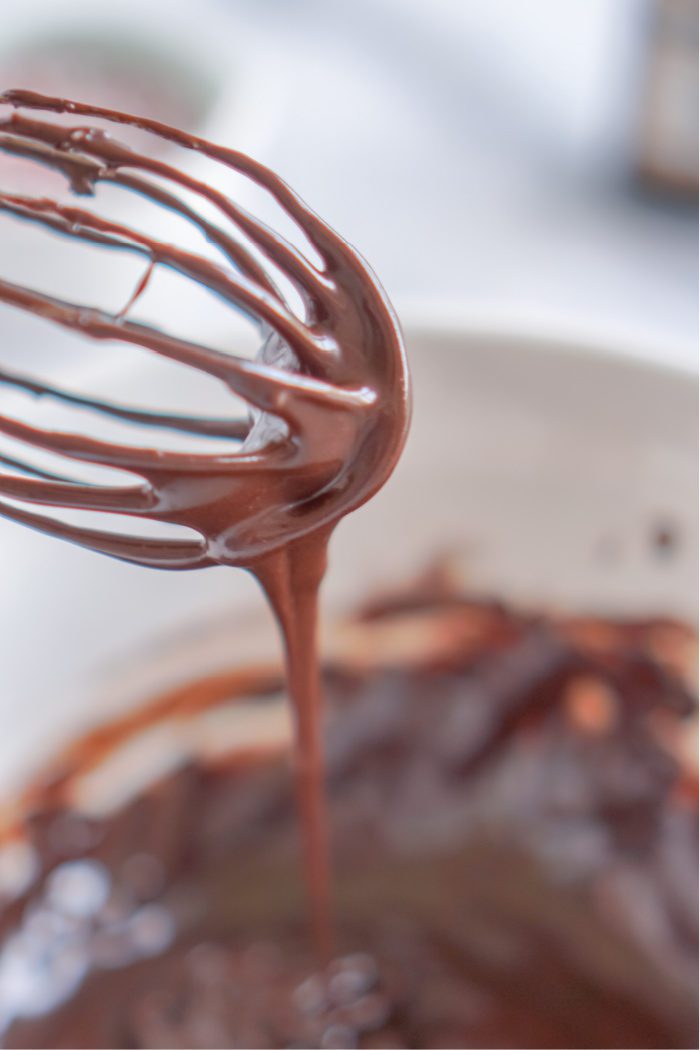 A whisk covered in melted chocolate.