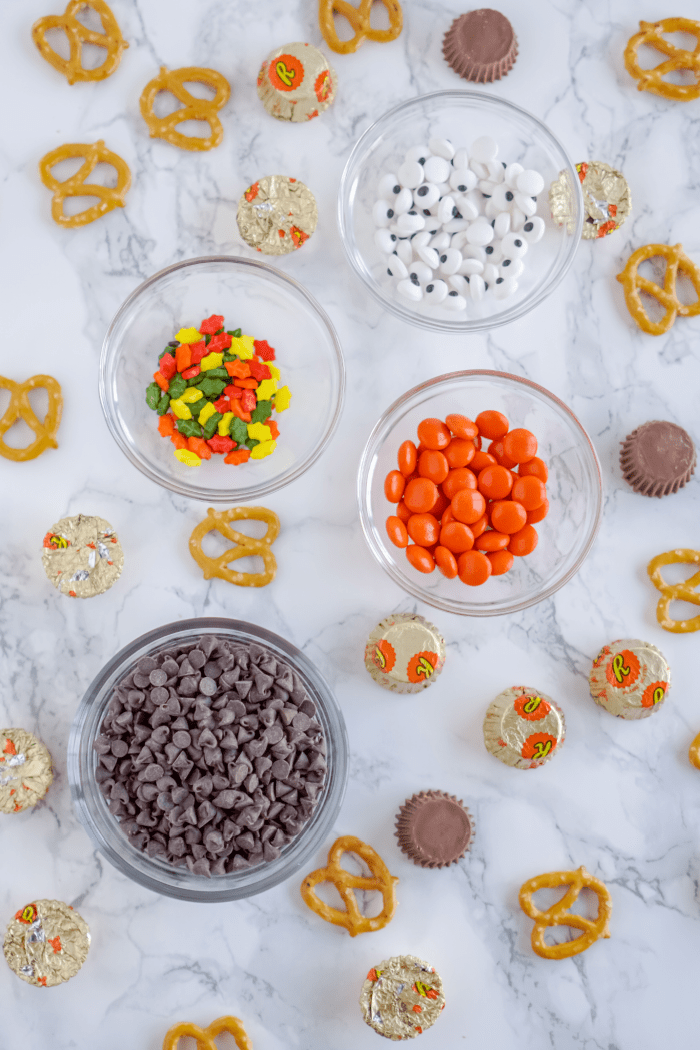 Various Halloween candies and pretzels on marble background.