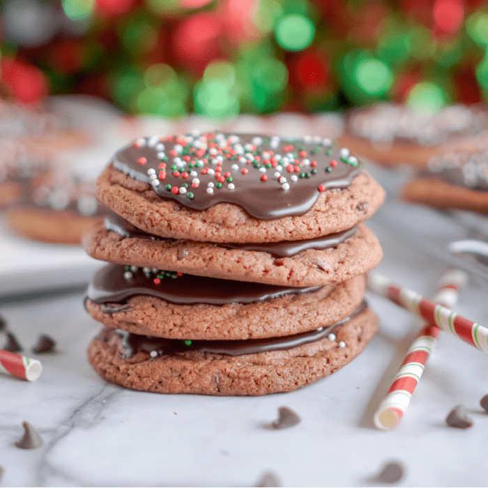 A stack of four chocolate cookies with red and green sprinkles.