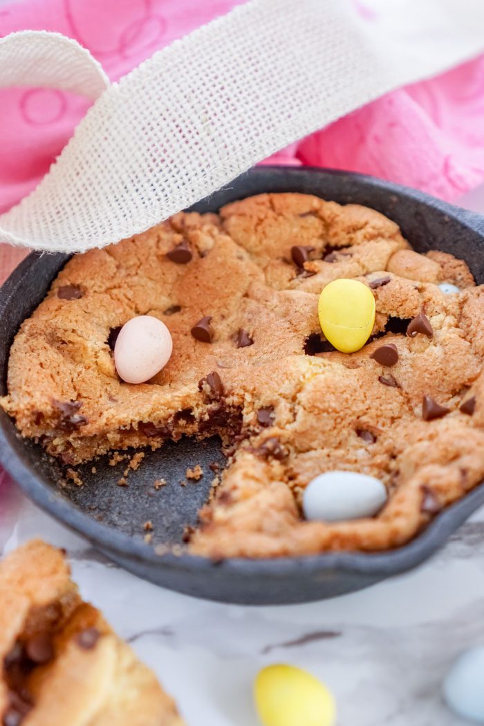 A chocolate chip cookie in a cast iron skillet.