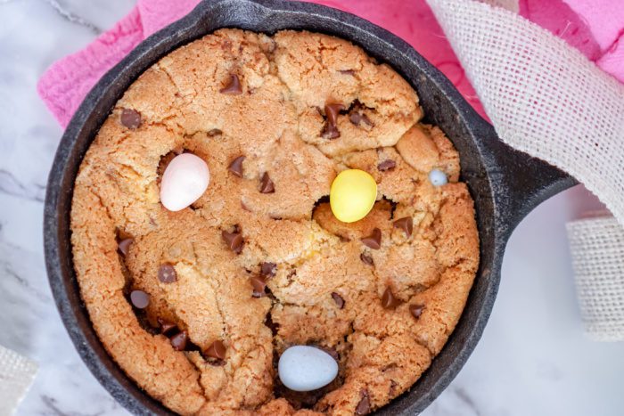 A chocolate chip cookie in a cast iron skillet.